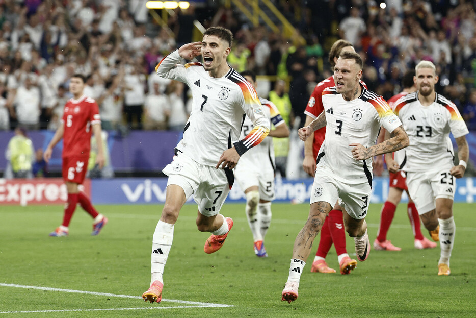 サッカーの欧州選手権は２９日、決勝トーナメント１回戦の２試合が行われ、開催国ドイツが準々決勝に進んだ。デンマークを２―０で下した。後半にハーバーツ（左手前）のＰＫで先制し、ムシアラが加点＝ドルトムント