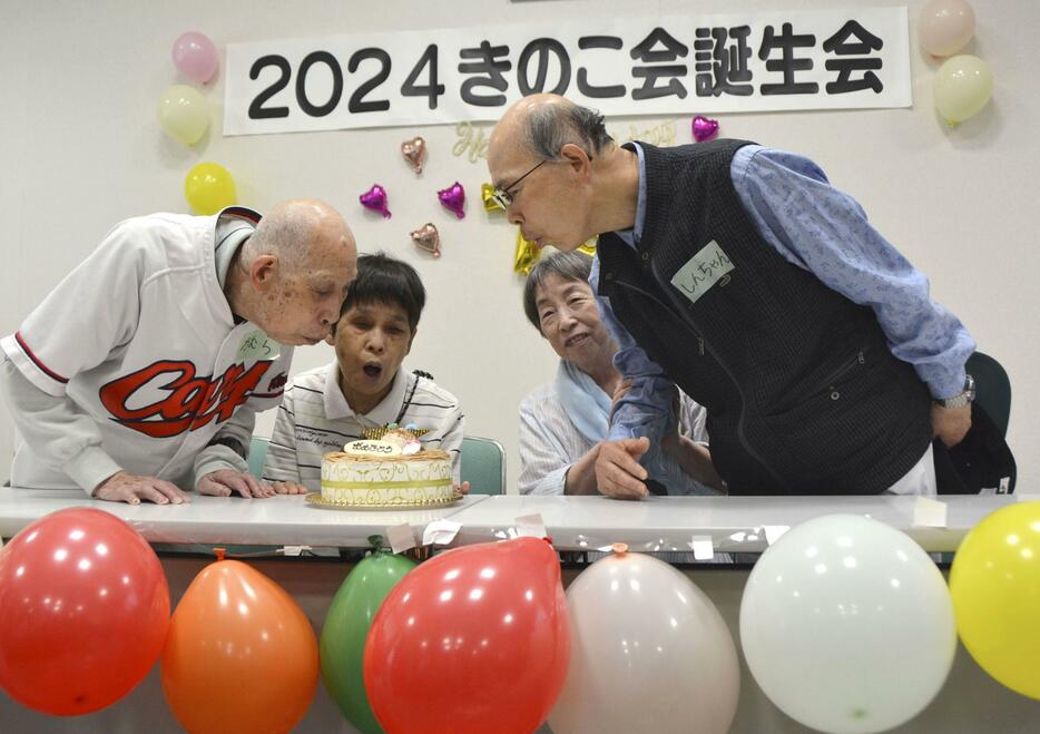 「きのこ会」の誕生会で、ケーキのろうそくの火を吹き消す原爆小頭症の被爆者＝22日午前、広島市