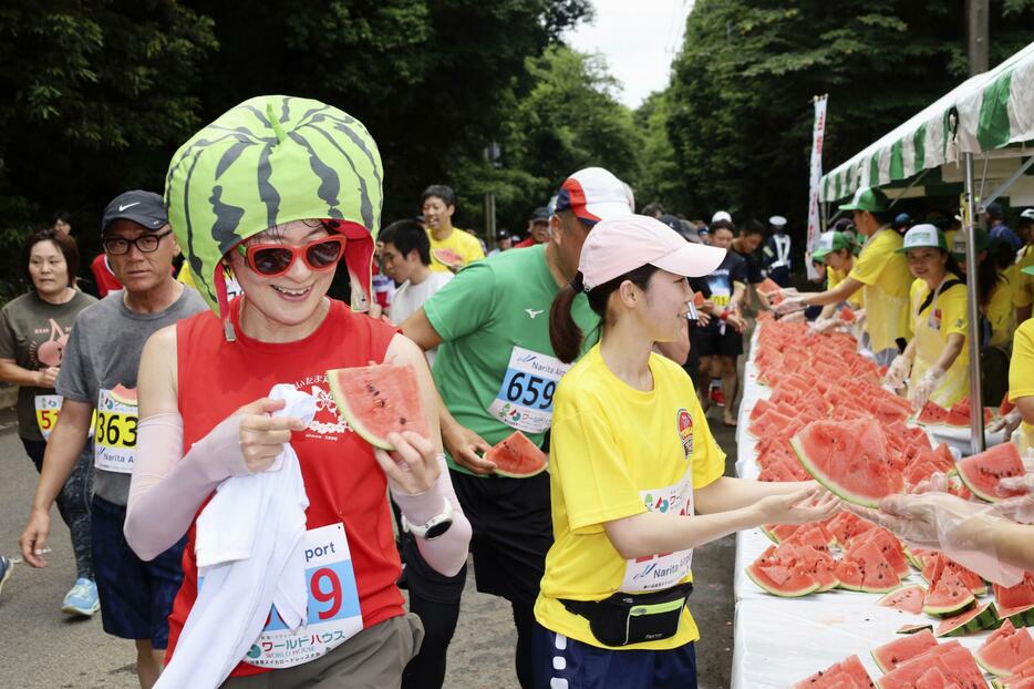 千葉県富里市で開かれたマラソン大会「富里スイカロードレース」で、スイカを手に取るランナーたち＝16日午前