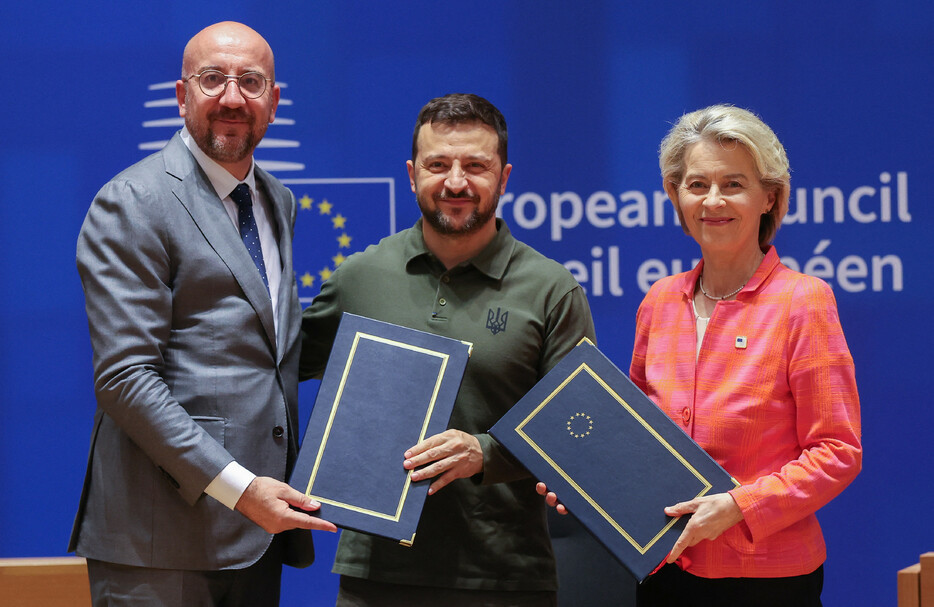 ２７日、ブリュッセルで行われた安保協定の署名式に臨むウクライナのゼレンスキー大統領（中央）と欧州連合（ＥＵ）のミシェル大統領（左）、フォンデアライエン欧州委員長。