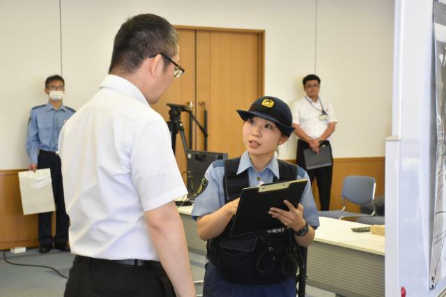 逃走車両の情報などを目撃者から聞き出す警察官＝２６日午前、宮崎市・県警本部