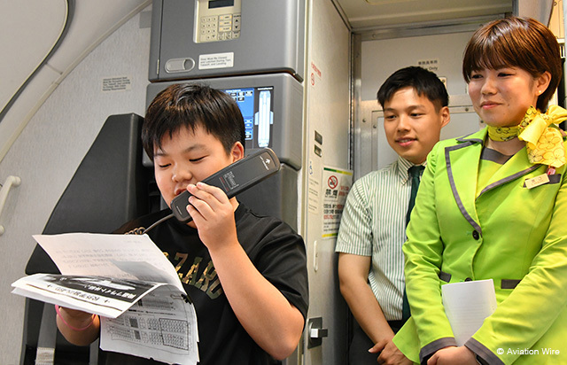 機内アナウンスに挑戦する児童（左）を見守るスプリング・ジャパンの客室乗務員＝24年6月24日 PHOTO: Yusuke KOHASE/Aviation Wire