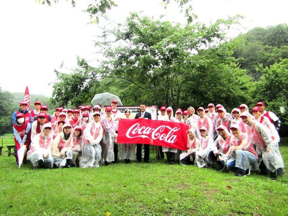 上川の里で大雨の中、初宿八王子市長を囲むコカ・コーラ社員