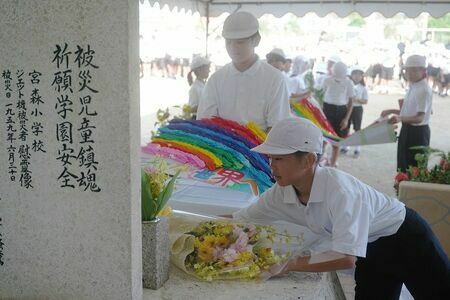 なかよし地蔵前に献花する児童＝28日、うるま市の宮森小（竹花徹朗撮影）