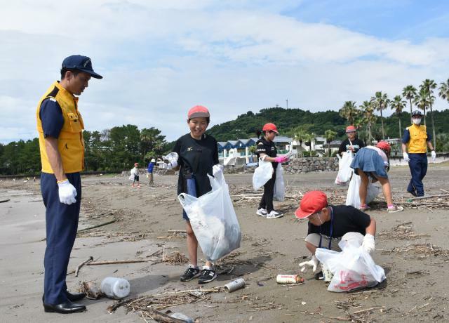 宮崎海上保安部の職員とごみを拾い集める大堂津小の児童たち