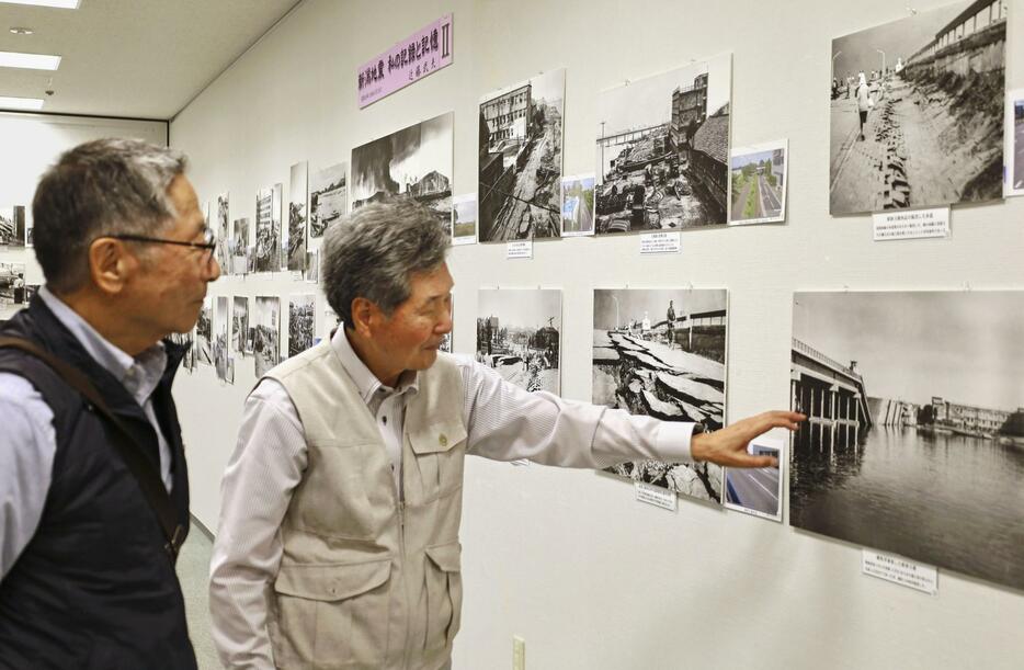 展覧会で、来場者（左）に写真の説明をする近藤武夫さん＝1日、新潟市