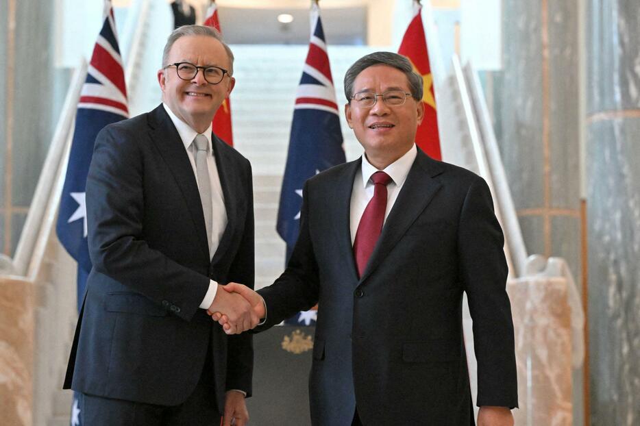 握手するオーストラリアのアルバニージー首相（左）と中国の李強首相＝17日、キャンベラ（ロイター＝共同）