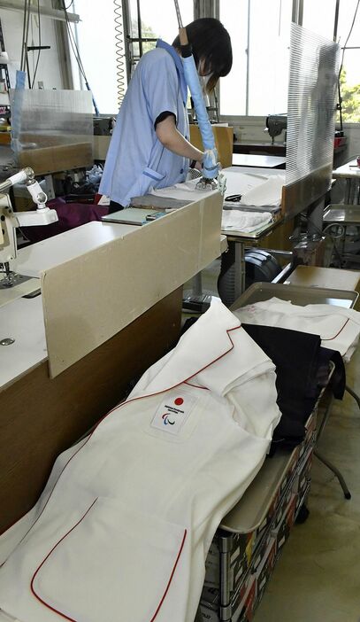 パリ・パラリンピック選手団のジャケット縫製を急ピッチで進める職員＝26日、六戸町