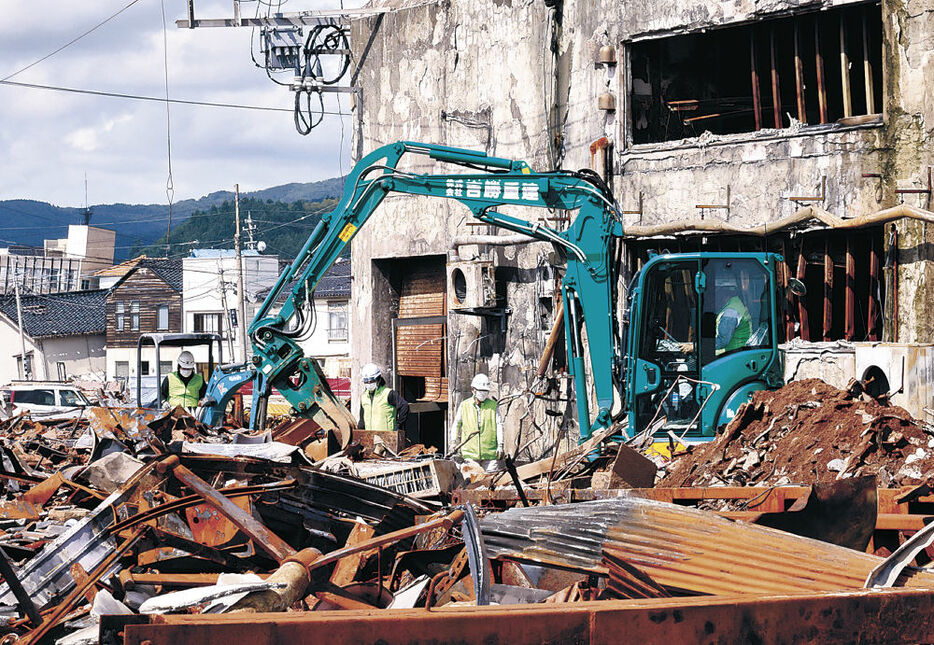 朝市通り沿いで重機による建物の取り壊しに取り掛かる作業員＝５日午前８時５０分、輪島市河井町