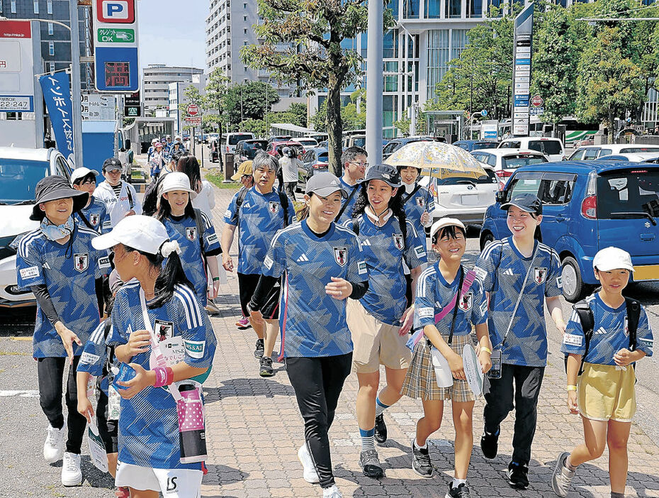 日本代表のユニホームを着て参加者と歩く澤さん（中央）＝８日午前１０時、金沢市広岡１丁目