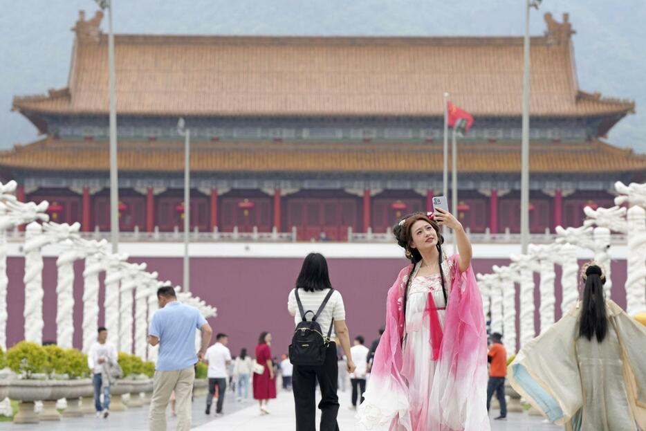 横店影視城で、紫禁城の屋外セットを背景に記念写真を撮る女性＝4月、中国浙江省東陽市横店鎮（共同）