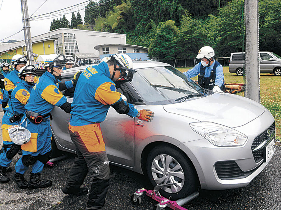 放置車両をミニレッカーで移動させる警官＝氷見市仏生寺公民館グラウンド