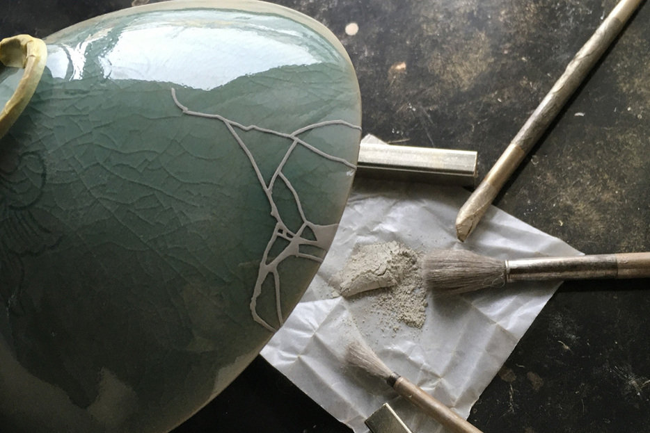 写真提供：monotsugi 「銀継ぎ」の一例。 青磁の茶碗に、粉筒（ふんづつ）という、葦（あし）にメッシュを張ったふるいのような道具を使い、銀粉を蒔いたところ。この後、漆で銀粉を固め、磨いて仕上げます。
