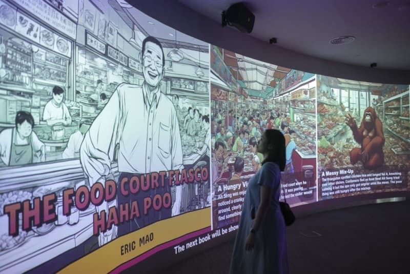 巨大パネルに映された、生成ＡＩが作成した物語や画像を見る女性＝２０２４年３月、シンガポールの中央図書館