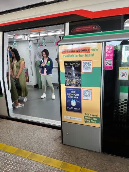 シンガポールの都市鉄道の駅のホームに掲げている電子書籍のポスター。国立図書館のアプリでＱＲコードを読み込むとレンタルできる＝２０２４年３月