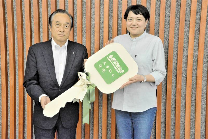 伊沢町長から鍵のレプリカを受ける入居者代表の長谷川さん（右）