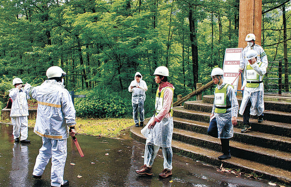 下山者役の参加者を誘導する警察官＝２８日午前１０時１５分、白山市白峰の市ノ瀬ビジターセンター