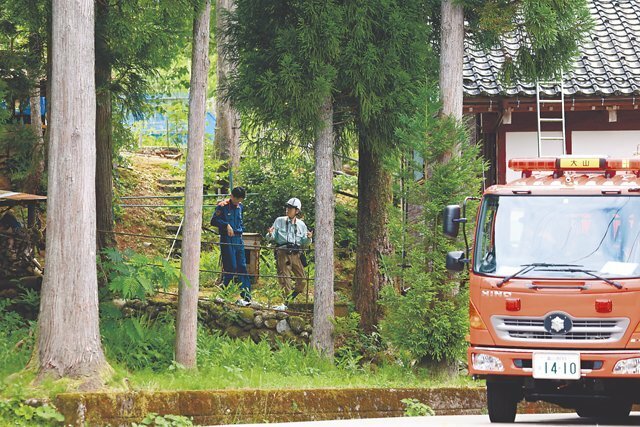 男性がクマに襲われた現場付近を調べる県職員と消防署員＝２１日午後１時半ごろ、富山市西小俣