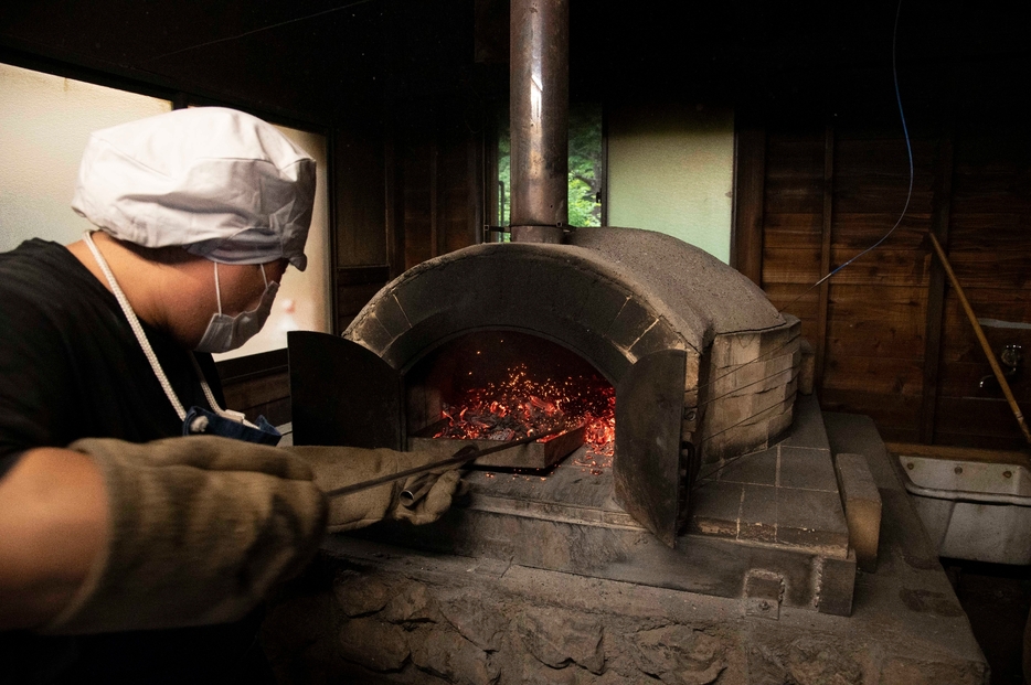 針葉樹と広葉樹の薪を使い分け、パン焼きに最適な温度まで石窯を温める赤津さん