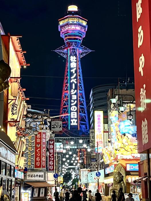 ［写真］南側から見た万博のイメージカラーで点灯する通天閣＝22日夜、大阪市浪速区で