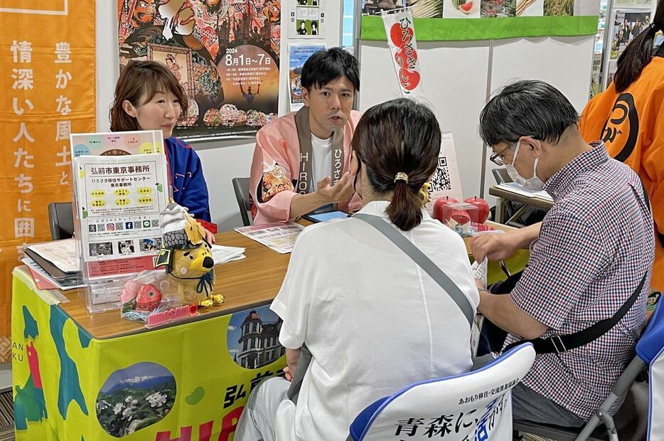 都内で開かれた移住イベントに出展し、来場者に説明する弘前市職員ら＝7月6日（同市提供）