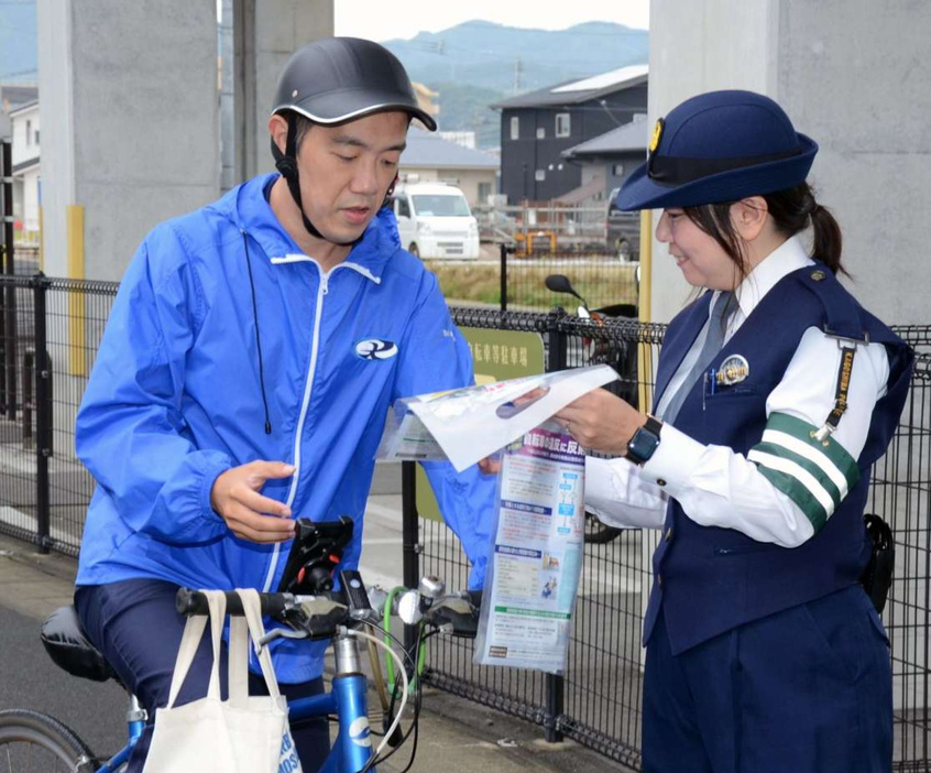 自転車利用者に道交法改正を周知する警察官＝１日、鹿児島市のＪＲ谷山駅