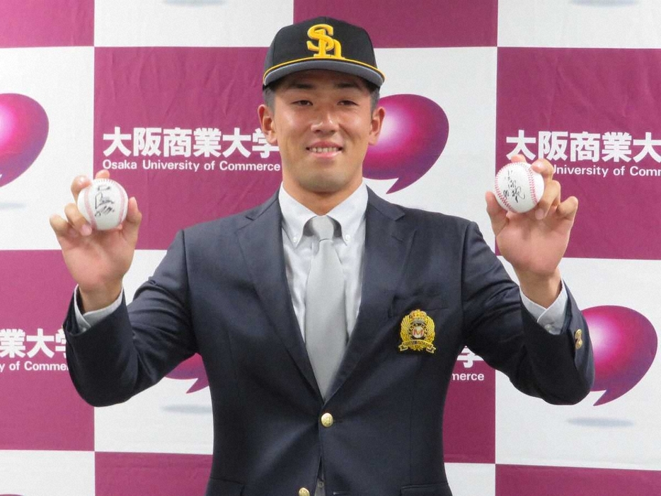 ソフトバンクから育成9位指名の挨拶を受けた大商大・岡田、右手に王会長、左手には小久保監督のサインボールを持つ