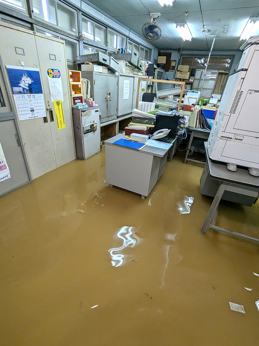 8日午後の事務所内。この時はくるぶしの上程度だった水位は翌朝には机を覆う高さに。机上にあったパソコンや書類のほとんどが水に漬かった＝8日午後3時15分ごろ、鹿児島県与論町立長（与論島製糖与論事業所提供）