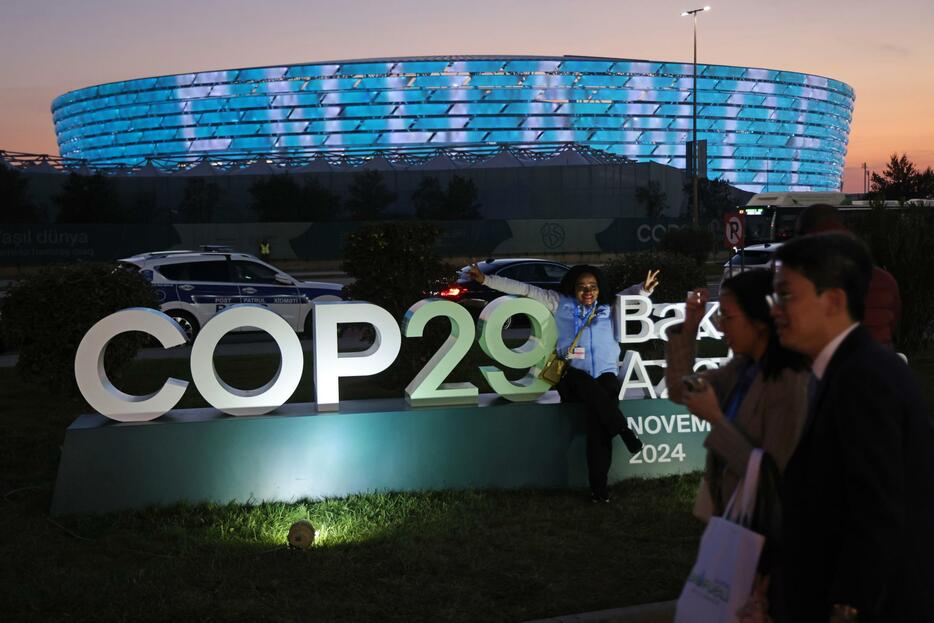 COP29の会場前で写真撮影をする人たち＝15日、バクー（ゲッティ＝共同）