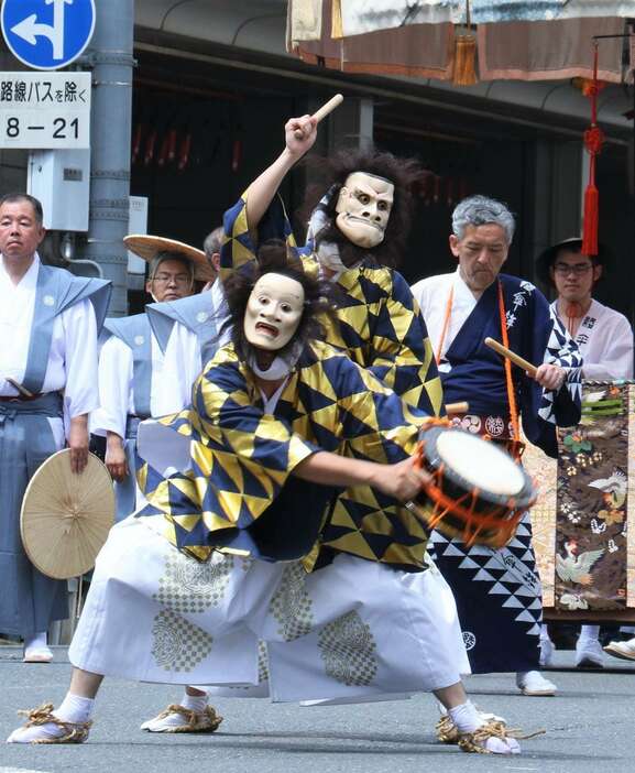 神面をつけて棒振り囃子を披露する綾傘鉾の太鼓方＝7月