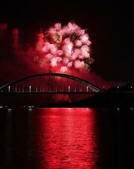 赤い光が秋空を幻想的に照らす。手前は伊万里湾大橋＝２３日夜、伊万里市の楠久津公園周辺