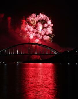 赤い光が秋空を幻想的に照らす。手前は伊万里湾大橋＝２３日夜、伊万里市の楠久津公園周辺