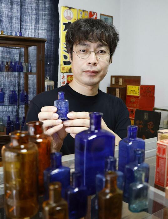 大正から昭和にかけて使われていたガラス製の薬瓶を集めている丸藤裕貴さん＝2024年9月、富山市