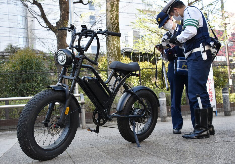 ペダル付き原付き自転車「モペット」を取り締まる警察官＝４月１０日、東京都渋谷区