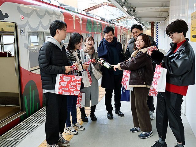 「富山もよう」を施した車両の前で地酒の魅力を語り合う参加者＝電鉄富山駅