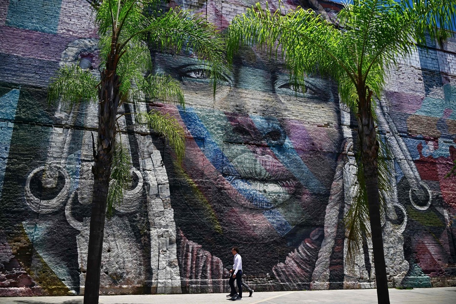 ブラジル・リオデジャネイロの港湾エリアで、ブラジル人アーティスト「コブラ」が描いたストリートアートのそばを歩く人々（2024年11月6日撮影）。【翻訳編集】 AFPBB News