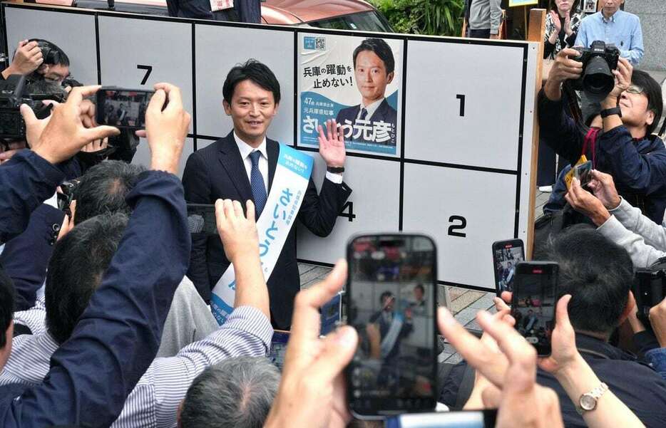 兵庫県知事選が告示され、自ら選挙ポスターを貼る斎藤元彦氏の姿を撮影する有権者ら＝10月31日午前、神戸市中央区（南雲都撮影）