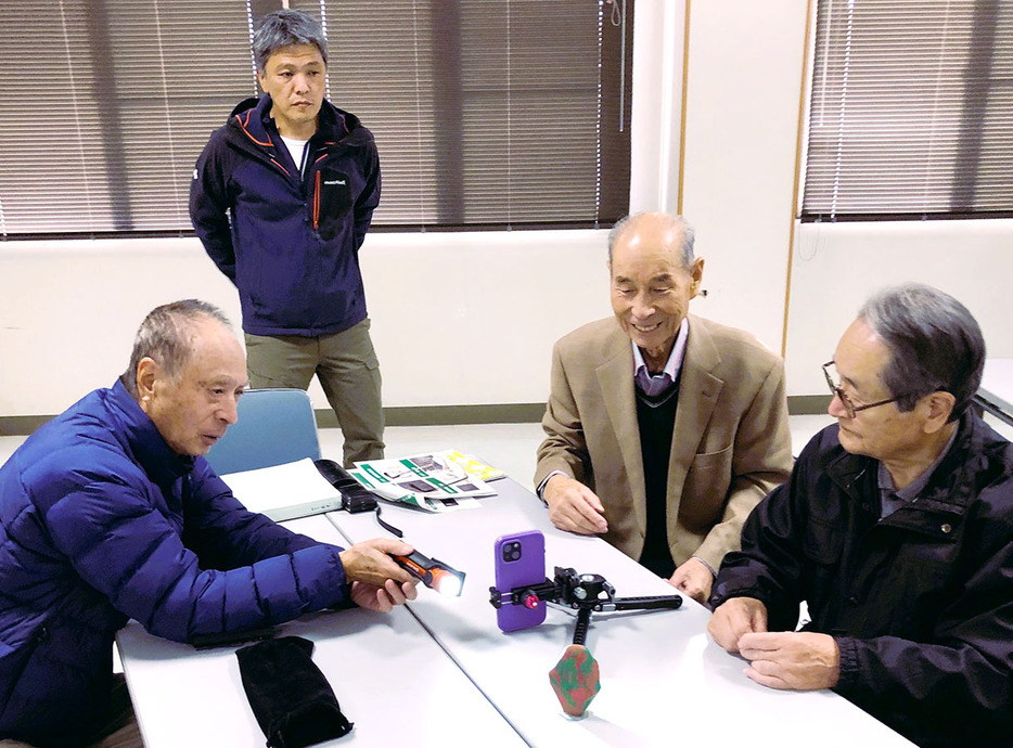 上椙さん（奥）からひかり拓本の技術を学ぶ郷土史研究会のメンバーたち＝多気町相可の町多気郷土資料館で