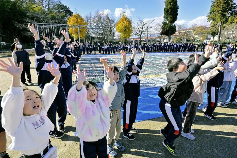 完成した「リスカの地上絵」を囲み記念撮影する児童たち=28日午後、大子町大子の町立だいご小