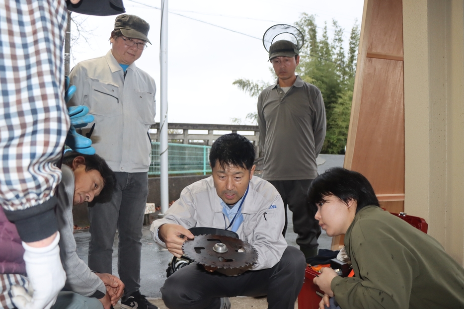 コマツ教習所の講師から刈払機の刃の仕組みを学ぶ住民たち＝兵庫県丹波市市島町下竹田で