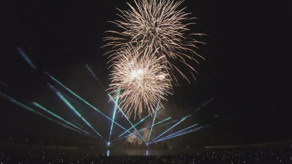 夜空を交錯する花火と音楽とレーザー光線のコラボレーション