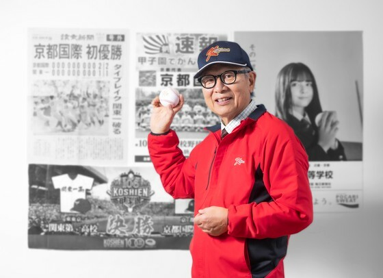 朴慶洙前校長が京都国際高校の甲子園優勝を報道した読売新聞号外と大会ポスターの前で優勝記念ボールを手にしている。キム・サンソン記者