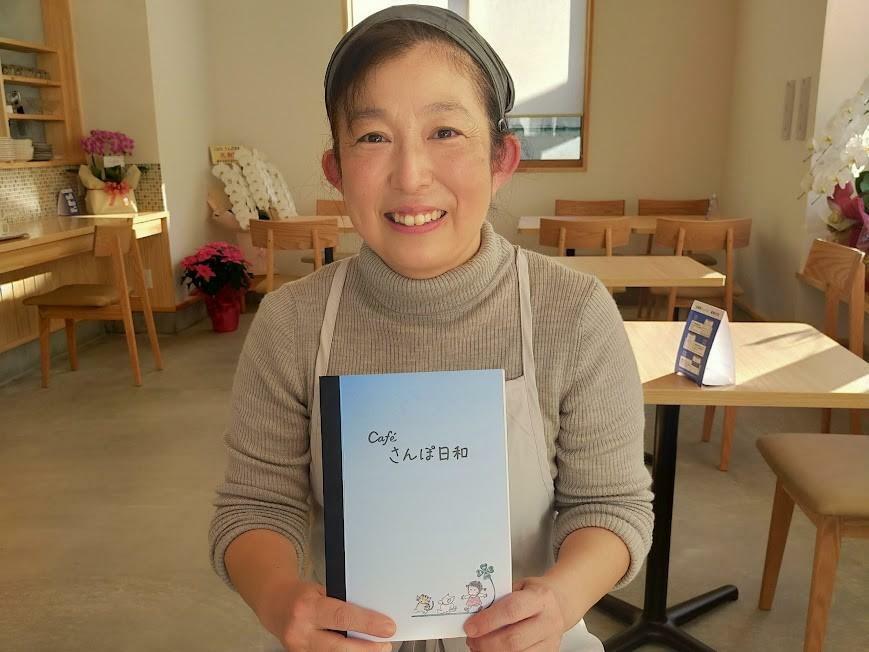 「優しい風合いに仕上がった」と自作のメニュー表を持つ店主の渡辺啓子さん