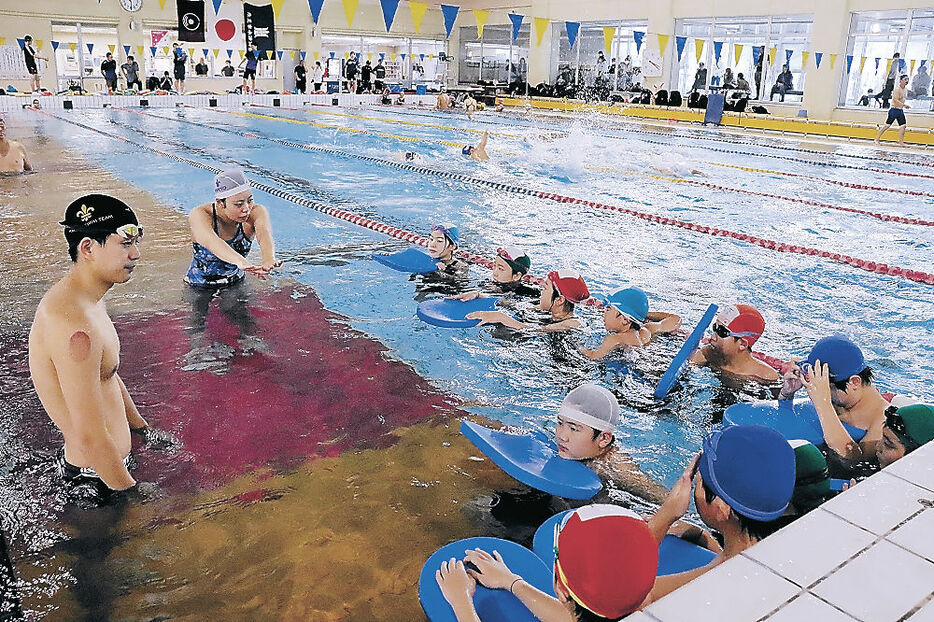 立教大の学生に教わり水泳の練習に取り組む児童＝氷見市民プール