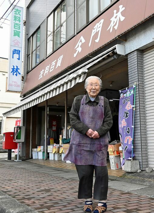 今年いっぱいで閉店する店の前に立つ吉田さん