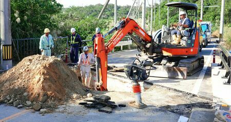 大雨の影響で陥没した国道３３１号の埋め戻し作業をする作業員＝１１日午後３時６分、東村平良（下地広也撮影）