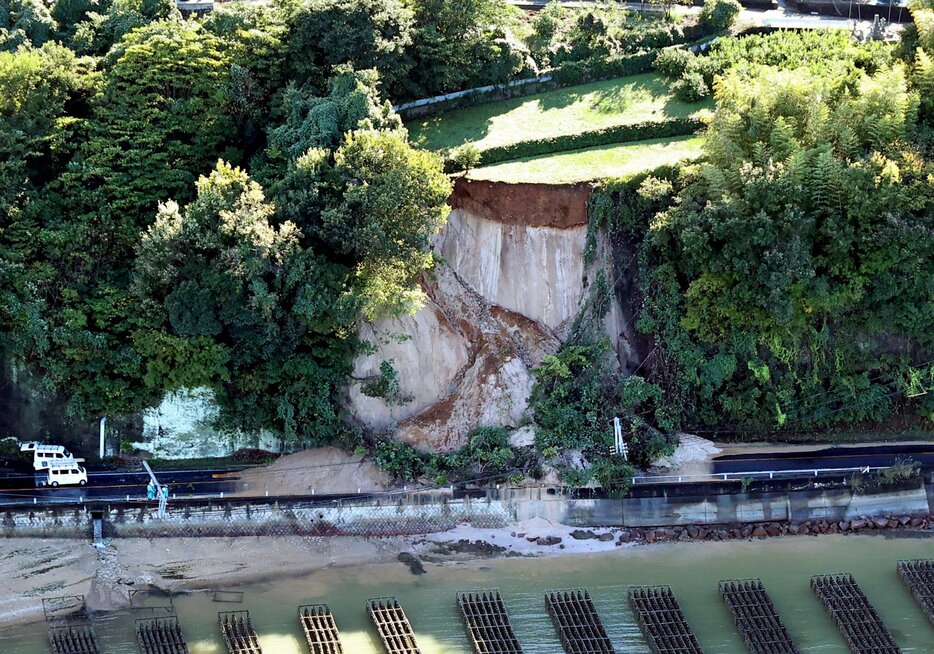 斜面が崩れ、土砂や木に覆われた県道（2日午後2時44分、江田島市沖美町）