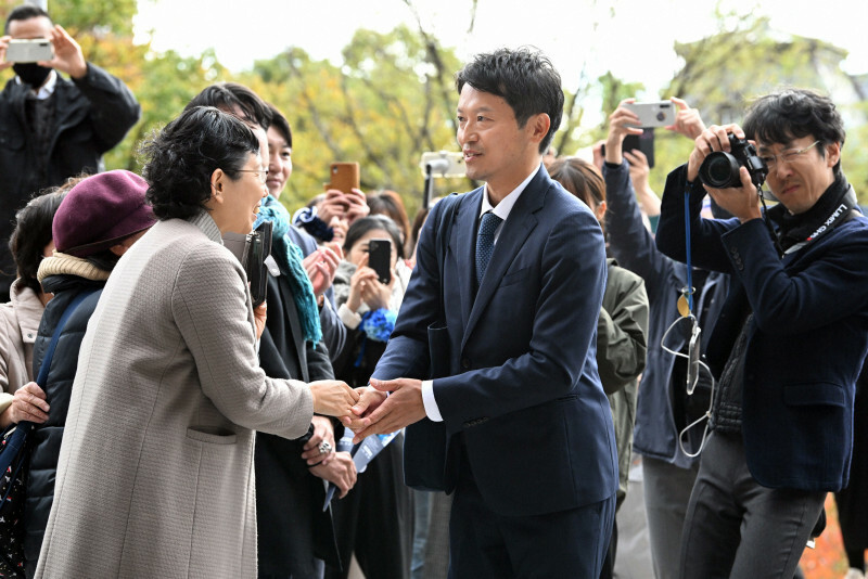 兵庫県知事選で再選を果たして兵庫県庁に登庁し、出迎えた支援者と握手する斎藤元彦氏（中央）＝神戸市中央区で2024年11月19日午前10時5分、大西岳彦撮影