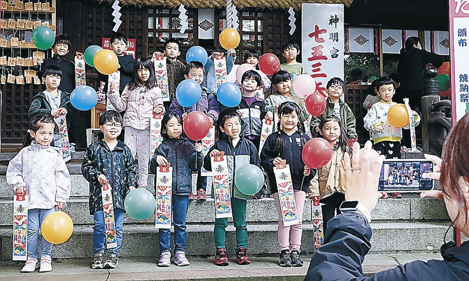 千歳飴を受け取り、笑顔を見せる園児＝金沢市野町２丁目の神明宮