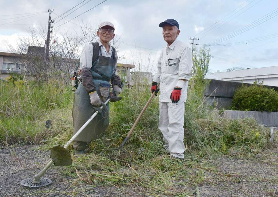 阿久根警察署で草刈りのボランティアに精を出す小田利雄さん（左）と鳥越廣信さん＝阿久根市赤瀬川